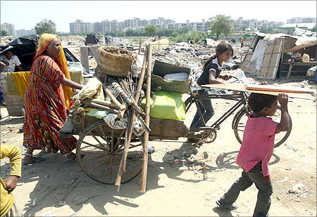 A family carries their belongings in a cycle rickshaw after they salvaged them from the debris of demolished shanties in Gurgaon.