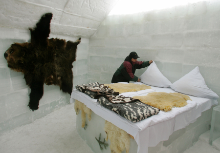 A woman arranges the bed in a room at the Balea Lac Ice Hotel in Romania.