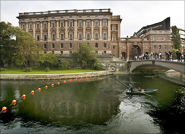 A fisherman lifts his net from a canal next to Sweden's Riksdagshuset, or Parliament Building.