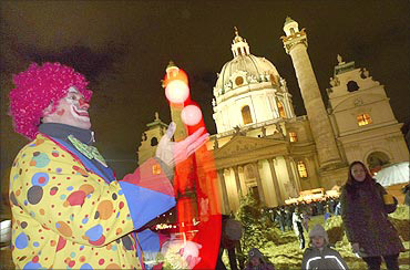 A clown juggles balls at a Christmas market in front of Karlskirche in Vienna.