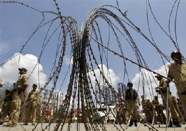 Policemen stand guard behind concertina wire barricade set up to stop Kashmiri protesters during a curfew in Srinagar.