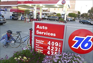 Eric Eastman fixes the wheel on his bicycle next to a board displaying gas prices at a petrol station in Los Angeles.