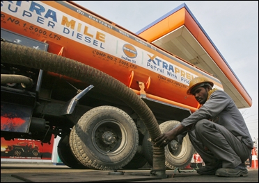 An employee refills petrol from a tanker at a fuel station at Noida.