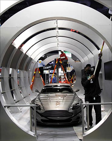 A worker cleans the Pioneer car audio booth displaying an Aston Martin DB9.