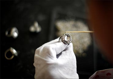 An employee sets stones on a replica of the British royal engagement ring at a jewellery factory.