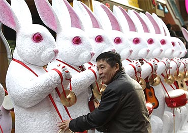 A resident plays in front of rabbit sculptures in Beijing.