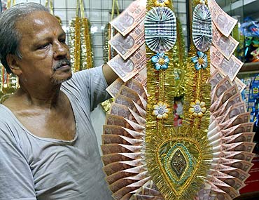 Dhanender Kumar Jain, 65, a shopkeeper, holds a garland made of Indian currency.