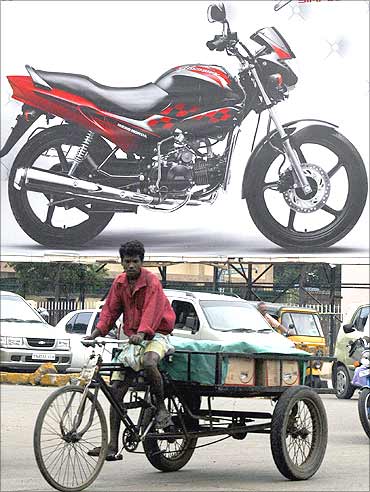 A vendor cycles past a billboard advertisement of a motorcycle in Chennai.