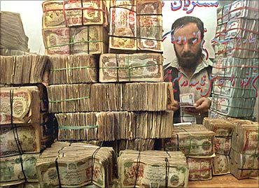 An Afghan money changer counts money at his shop in Kabul.