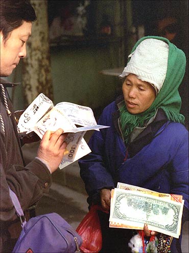 A Chinese woman sells enlarged copies of various currency notes.