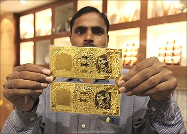 A salesman displays gold plates in the form of the Indian rupee note at a jewellery showroom.