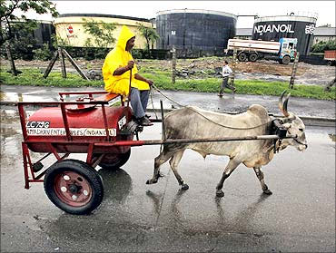 A worker transporting kerosene in a bullock cart travels past Indian Oil Corporation's fuel depot in Mumbai.