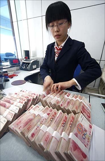 An employee counts Yuan banknotes at the Suining City Commercial Bank in Suining.