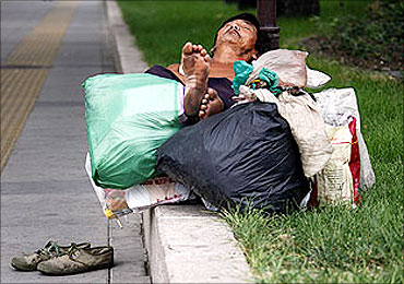 A homeless man sleeps with his possessions on the footpath near Tiananmen Square in Beijing.
