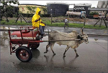 A worker transporting kerosene in a bullock cart travels past Indian Oil Corporation's fuel depot in Mumbai.