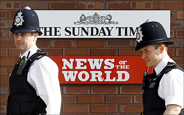 Police officers stand outside an entrance to News International in London.