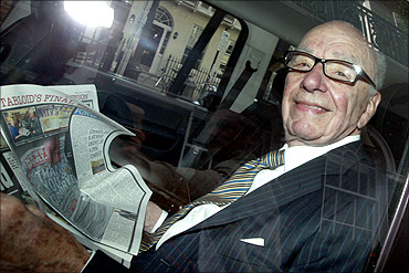 News Corporation CEO Rupert Murdoch holds a copy of The Sun as he is driven away from his flat.