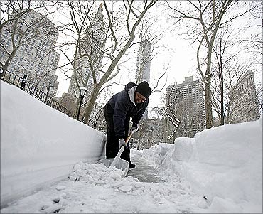 A worker shovels snow from the sidewalk in front of the New York Stock Exchange after a snow storm.