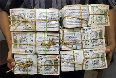 An employee carries bundles of currency notes.