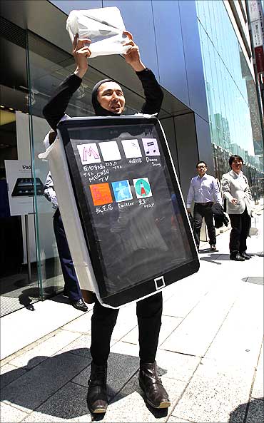 A man in a costume representing an iPad poses with his iPad in Tokyo.