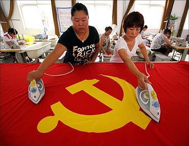 Workers use irons to smooth out a Communist Party of China flag at the Beijing Jingong Flag factory.