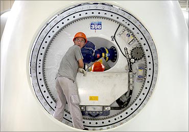 A worker leans inside the shell of a wind turbine tower in the assembly workshop.