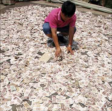 A 35-year-old man spreads one jiao and two jiao banknotes to dry in the sun in Kaili, Guizhou.