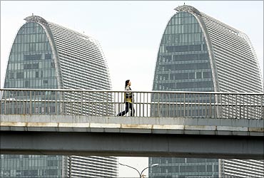 A woman walks on a pedestrian bridge in front of office buildings in Beijing.