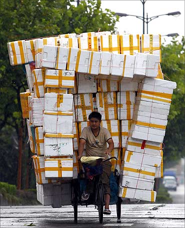A Chinese man rides his tricycle laden with recyclable styrofoam along a main road in Shanghai.