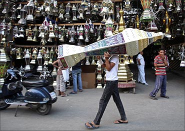 A man carries a traditional lantern called fanous in front of a shop selling lanterns on a street in Cairo.