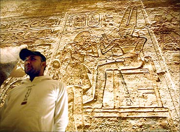 Man examines etchings inside temple of Abu Simbel at sunrise.