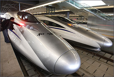 A man looks at the bullet trains serving the high-speed railway linking Shanghai and Hangzhou in Sha