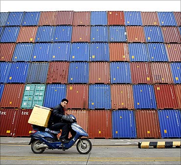 A man rides his motorcycle past shipping containers at the Port of Shanghai.