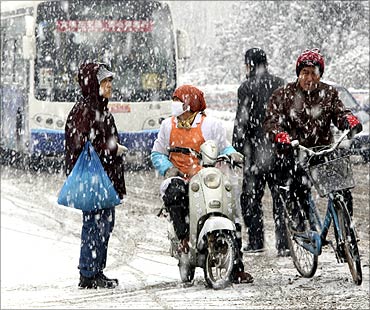 People make their way on a street amid snowfall in Yantai, Shandong province.