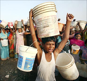 Slum dwellers shout slogans as they carry empty containers during a protest.