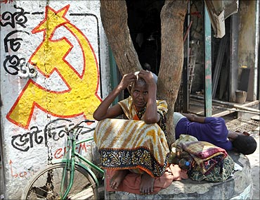 A woman sits under a tree next to a logo of the Communist Party of India.