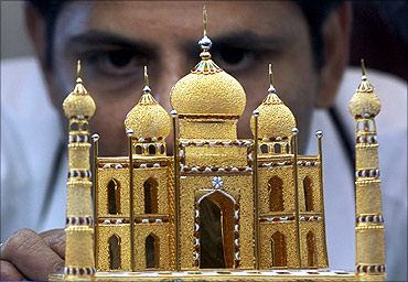 A worker displays a miniature 22 carat gold replica of the historic Taj Mahal.