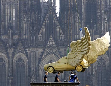 Workers install the sculpture 'Golden Bird' by German artist HA Schult in front of the cathedral.