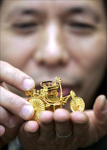 Taiwanese gold sculptor Jeng Ying-shie holds up a 108-gram mini gold sculpture of a Benz Motorwagen.