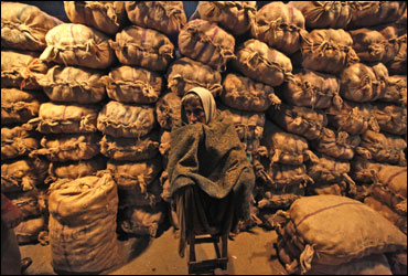 A vendor sits in front of sacks filled with potatoes at a wholesale vegetable market in Kolkata.