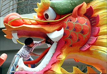 An artist puts finishing touches on a huge dragon display outside a Singapore shopping mall.