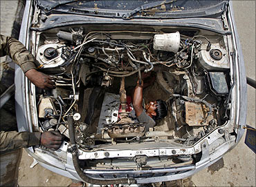 A mechanic dismantles the engine of a car at a workshop in Noida.