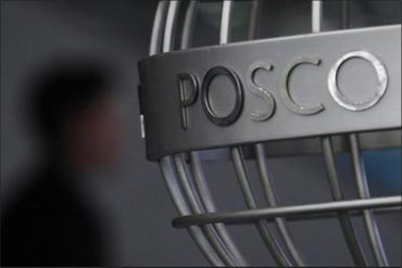 A man walks past a Posco logo.