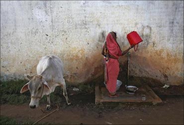 A woman empties a bucket at a transit camp for villagers.