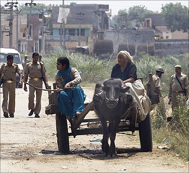 Police patrol as villagers ride past in a buffalo cart in UP.