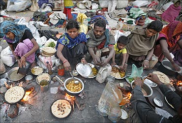 Homeless people prepare food on a roadside in Ahmedabad.