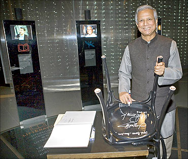 Muhammad Yunus signs the bottom of a chair whilst visiting the Nobel Museum in Stockholm.
