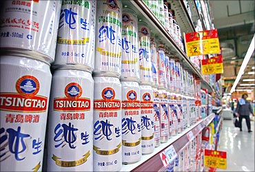 A customer walks past Tsingtao beer cans at a supermarket in Nanjing.
