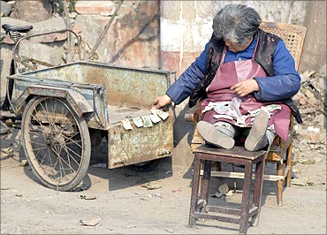An elderly woman counts small yuan notes on a street in Xiangfan, central China's province.