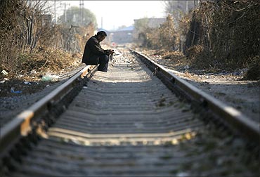 A Chinese man sits on train tracks in a rundown area located on the outskirts of Beijing.